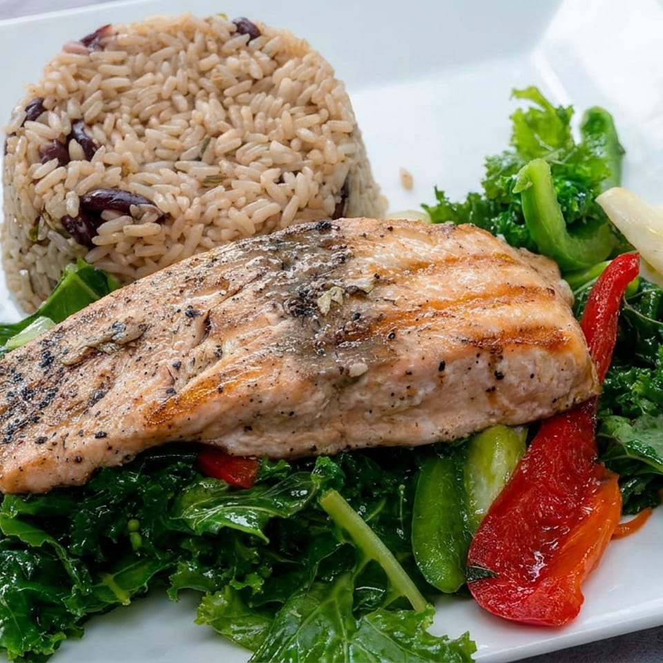 Grilled salmon fillet served with wild rice, sautéed kale, and colorful bell peppers on a white plate.